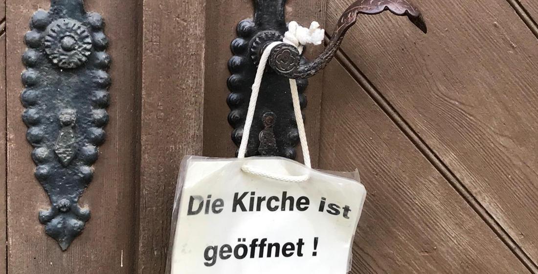  Kirchentürklinke mit Schild "Die Kirche ist geöffnet"