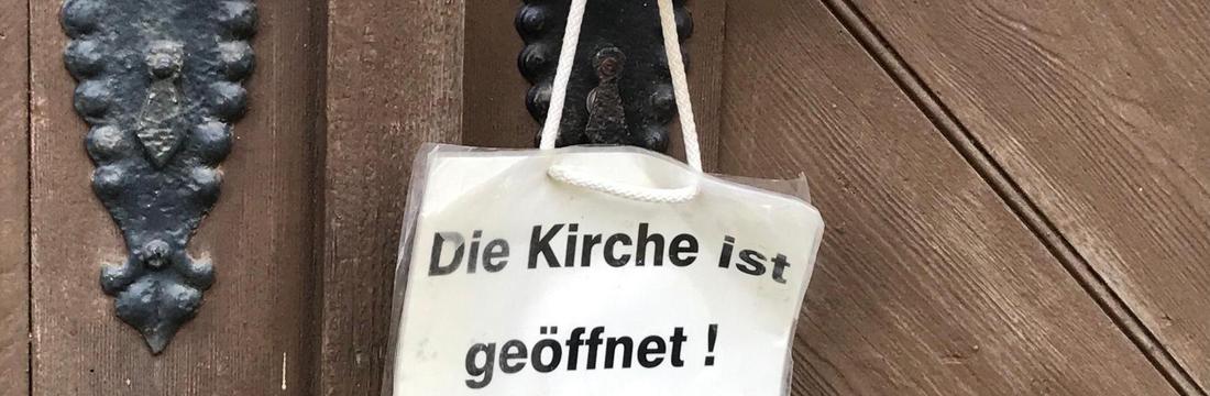  Kirchentür mit Schild: "Die Kirche ist geöffnet"