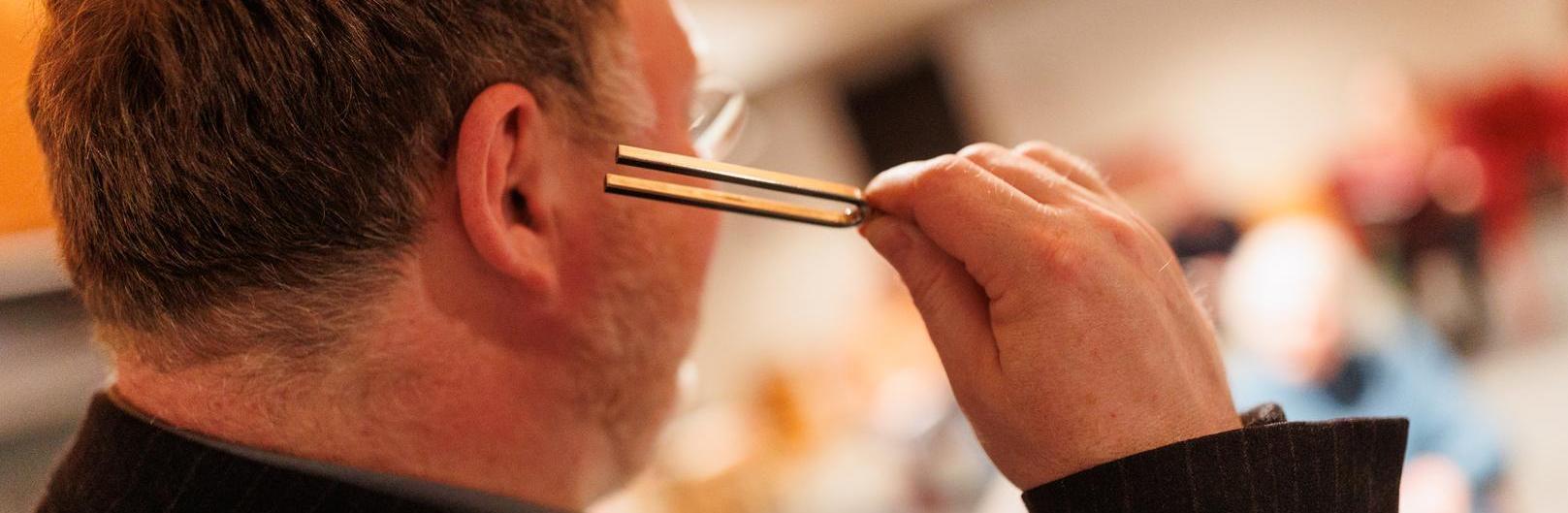 Mann mit Stimmgabel am Ohr