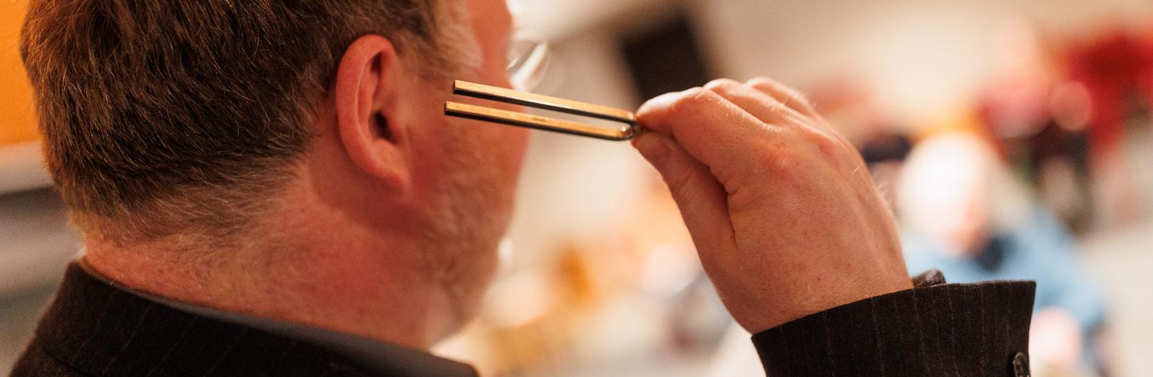 Mann mit Stimmgabel am Ohr