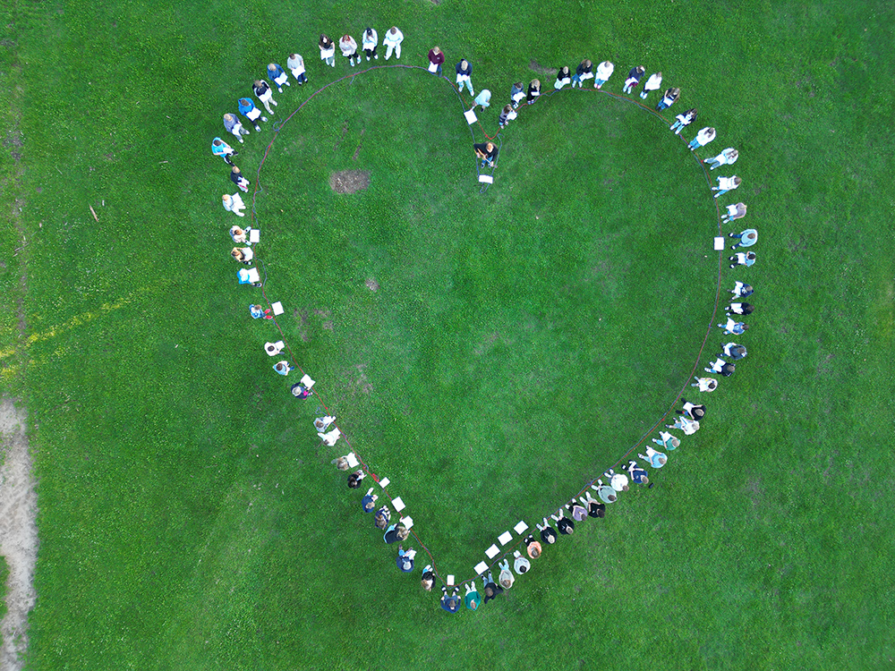 02_10.7.23_Kongeadalen 2023 Montag Ein großes Herz aus Menschen auf grünem Rasen; Foto: Lasse Neumann